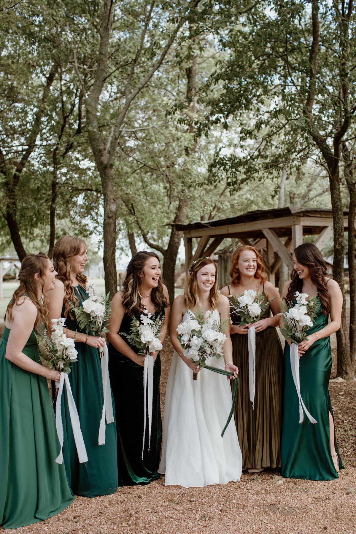 A candid laughing moment of bridesmaids in long green dresses at Chapel Creek Ranch in Denton Texas. Captured by Fort Worth Wedding Photographer, Megan Christine Studio