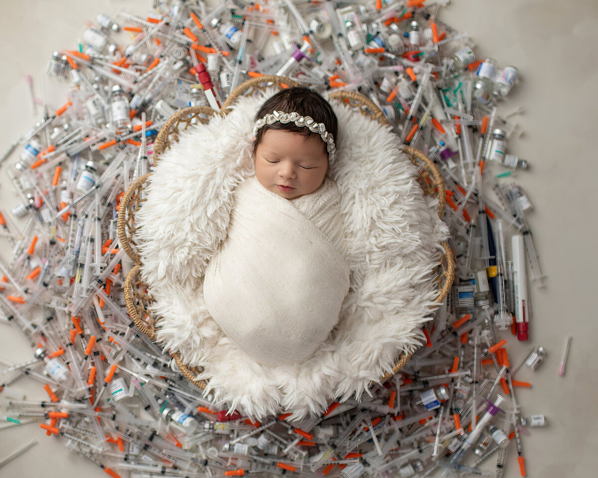baby surrounded by IVF needles