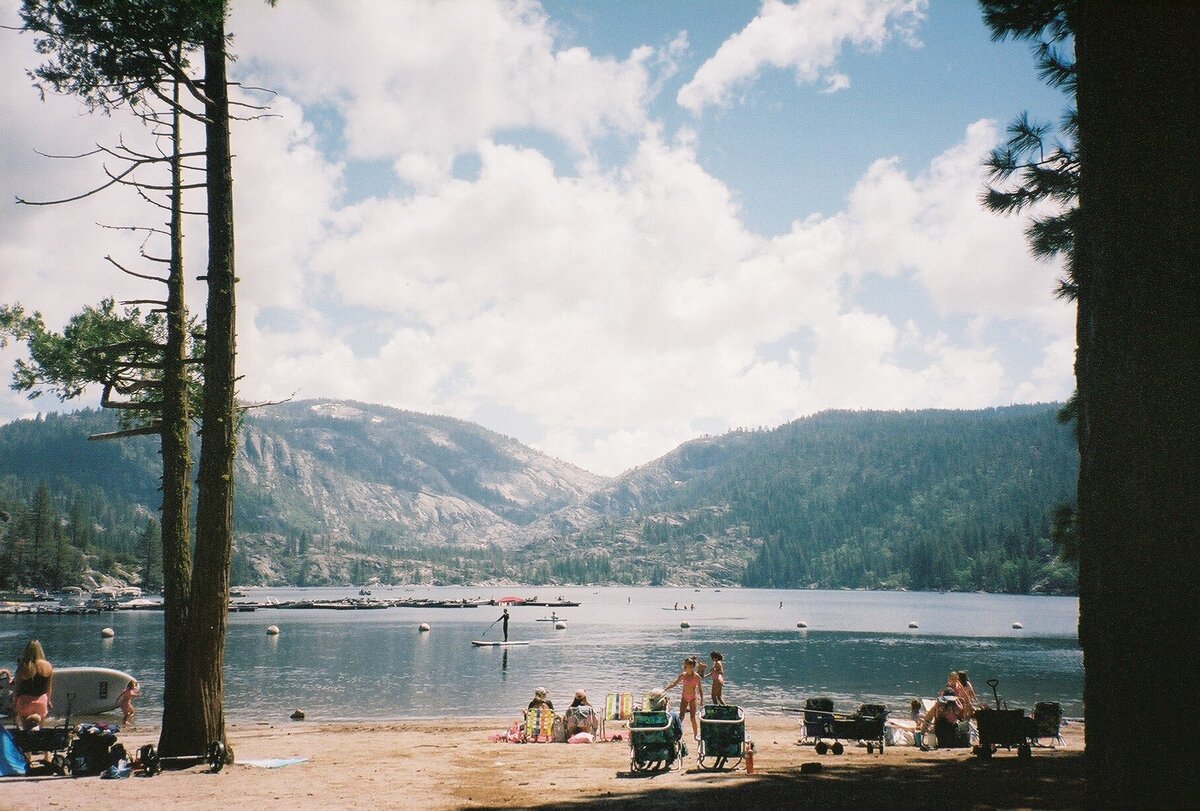 Lawn chairs by Pinecrest Lake captured on analog film by Kate Winters Photography, showcasing a peaceful, nostalgic moment by the water in an authentic, documentary style.