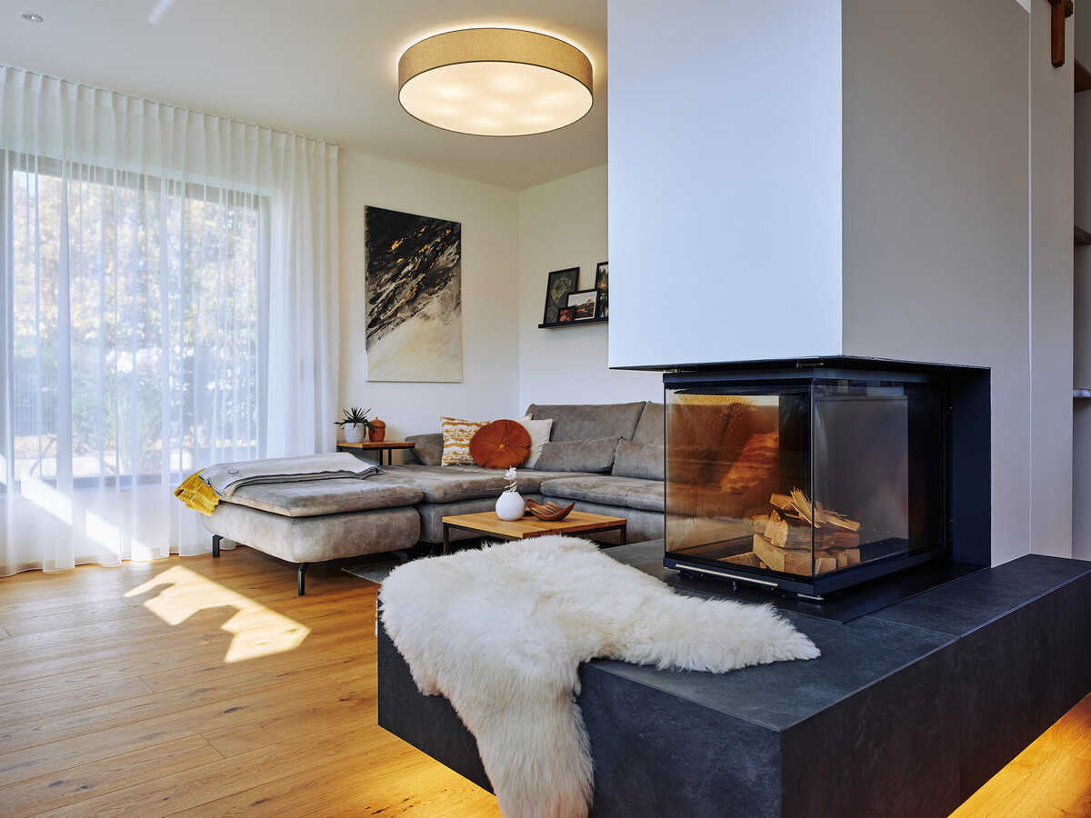 Offener Wohnraum mit modernem Essbereich, Designküche und dreiseitigem Kamin – hochwertige Interiorfotografie für Architekturprojekte in Österreich.