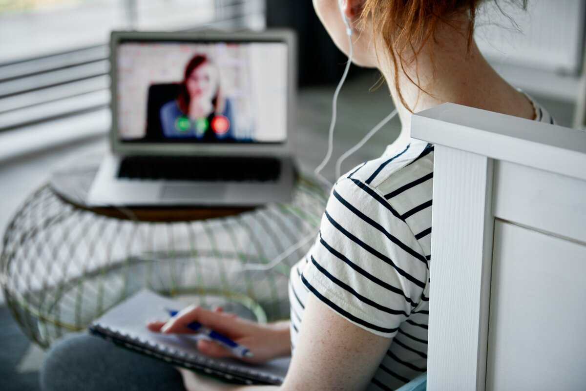 woman takes notes while on a video call