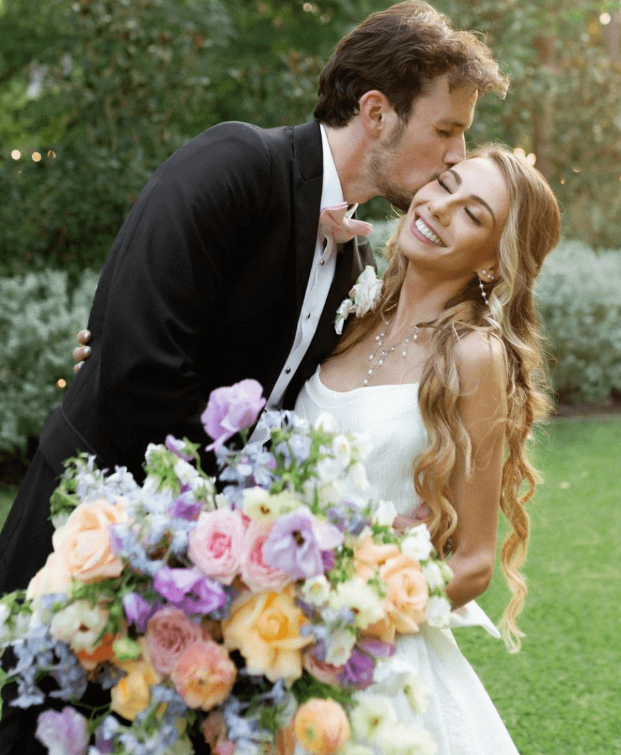 Bride with long romantic curls and glowing makeup embraces groom after receiving professional bridal hair and makeup by Mistique Makeup in Dallas, Texas