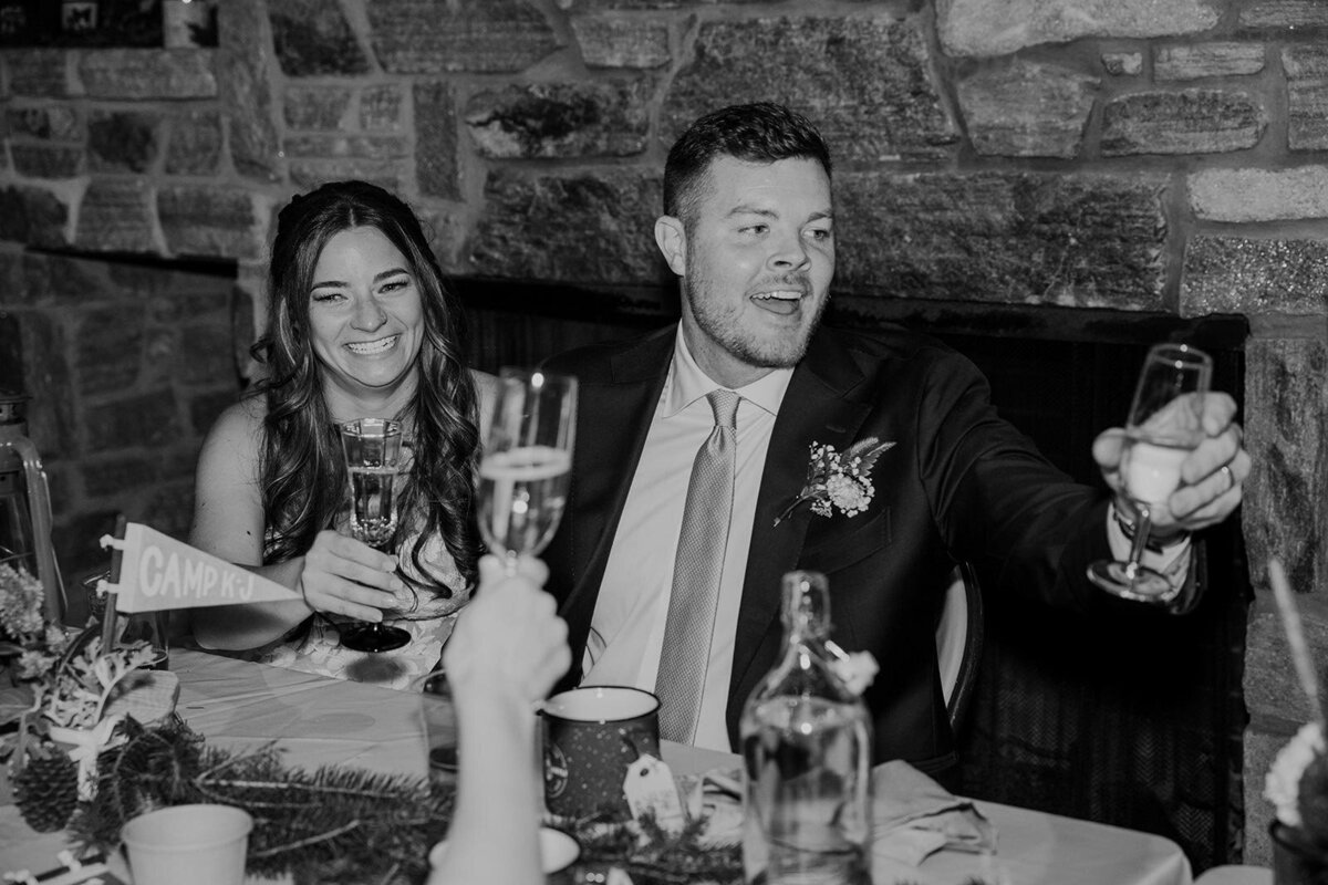A bride and groom raise a glass and react to a toast on their wedding day.
