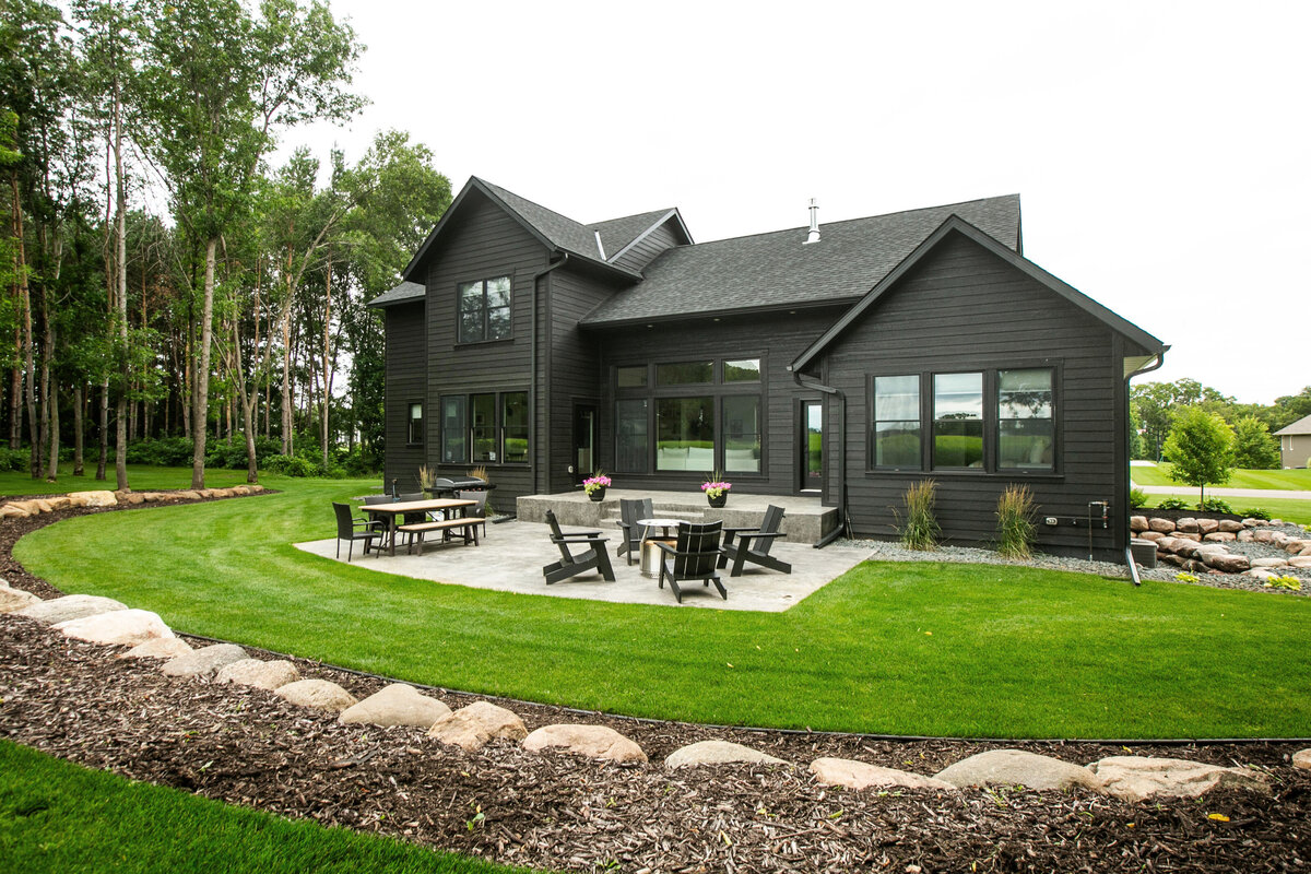 Exterior view of custom home in Otsego, Minnesota with black siding, large patio and windows built by Cornerstone Custom Builds