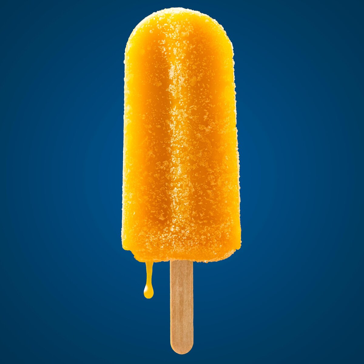 Orange mango popsicle with small drip.