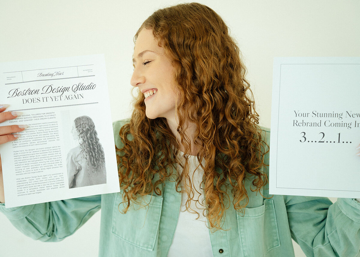 Brand and web designer Haylee Harris holding branded papers advertising Bostron Design Studio.