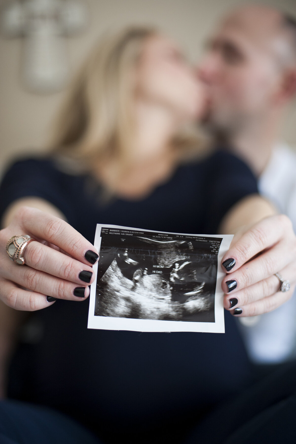 A couple kissing as they hold out an ultrasound image 