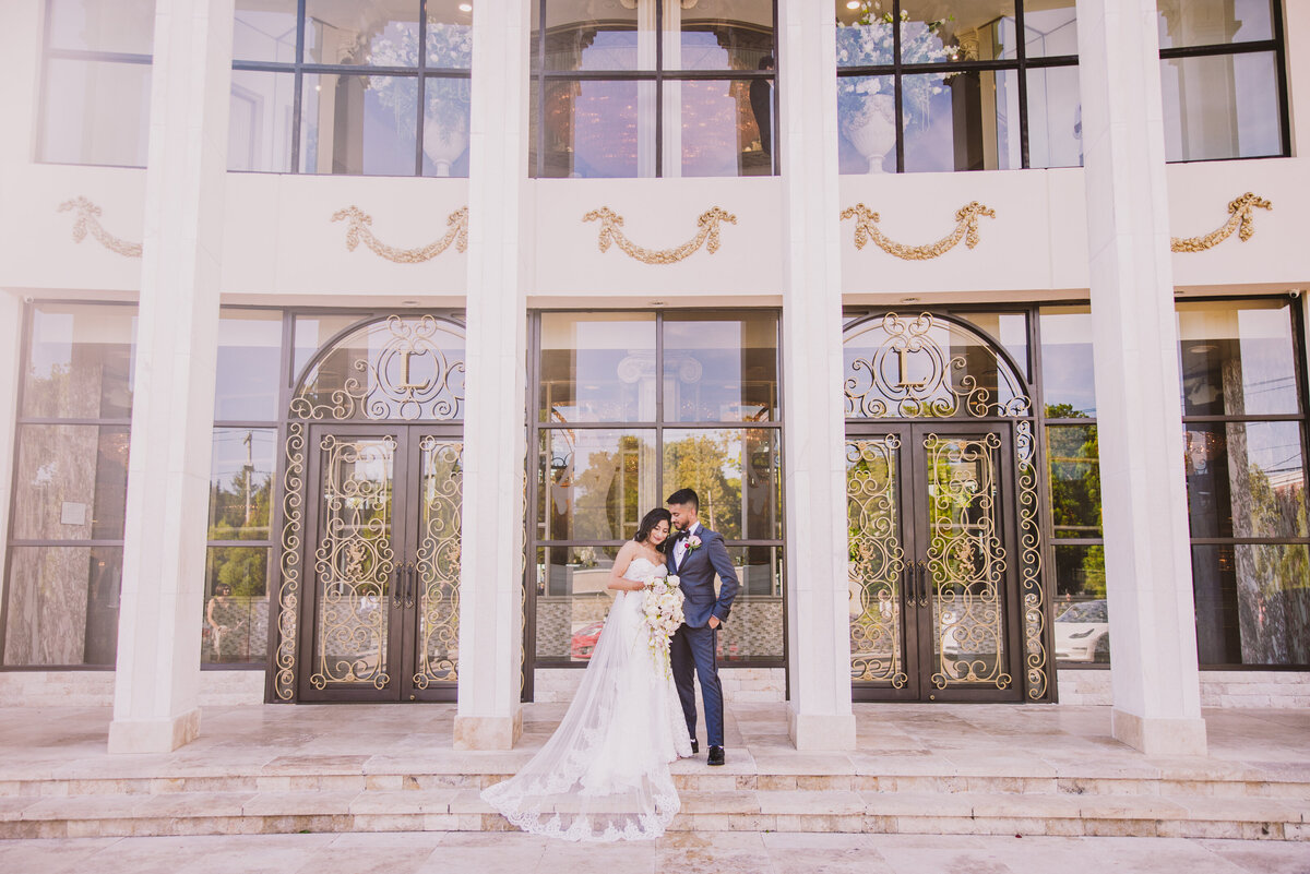 An indian christian wedding couple in a white dress sharing a moment in front of the leonards palazzo in great neck ny
