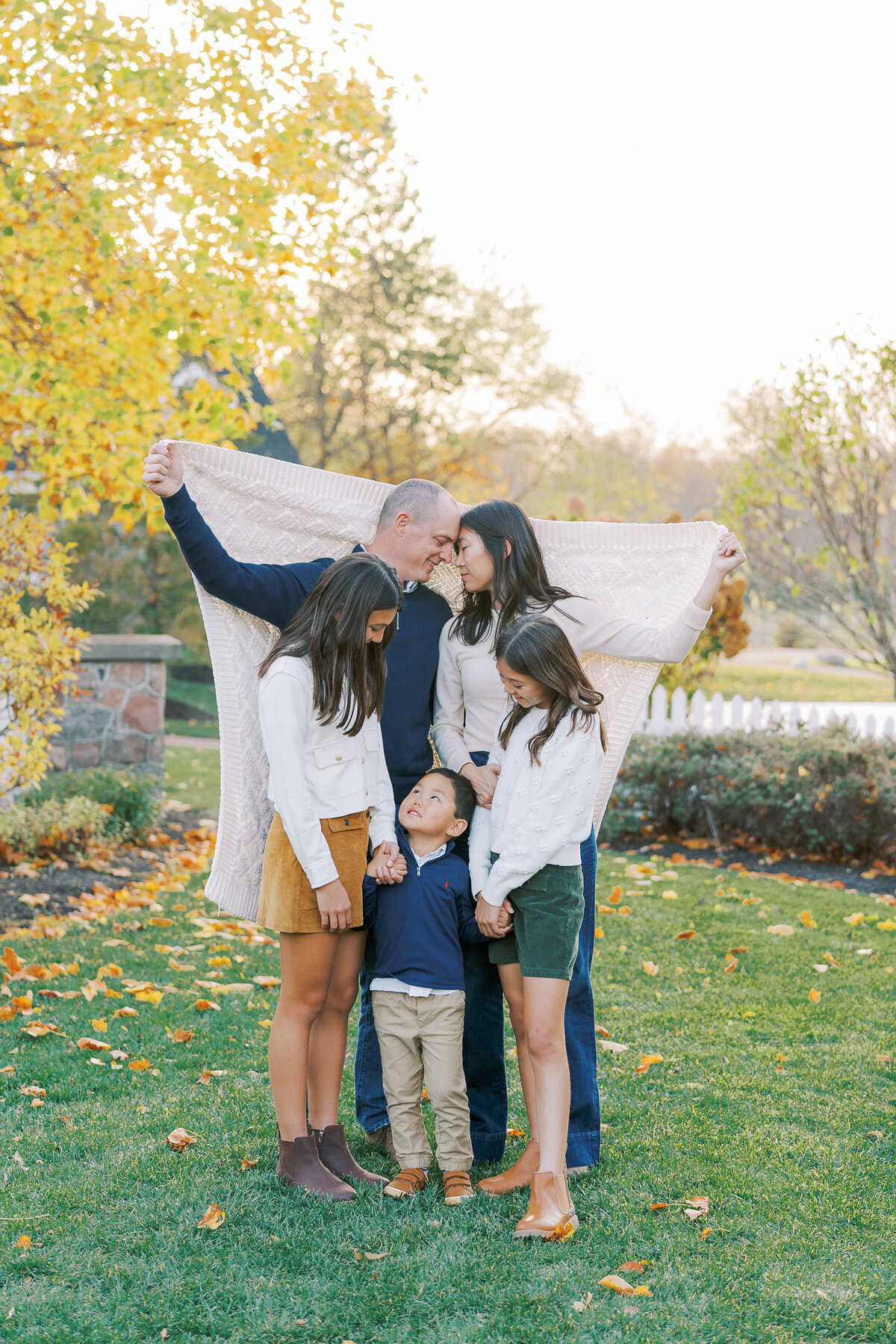 mom and dad holding up blanket around three kids