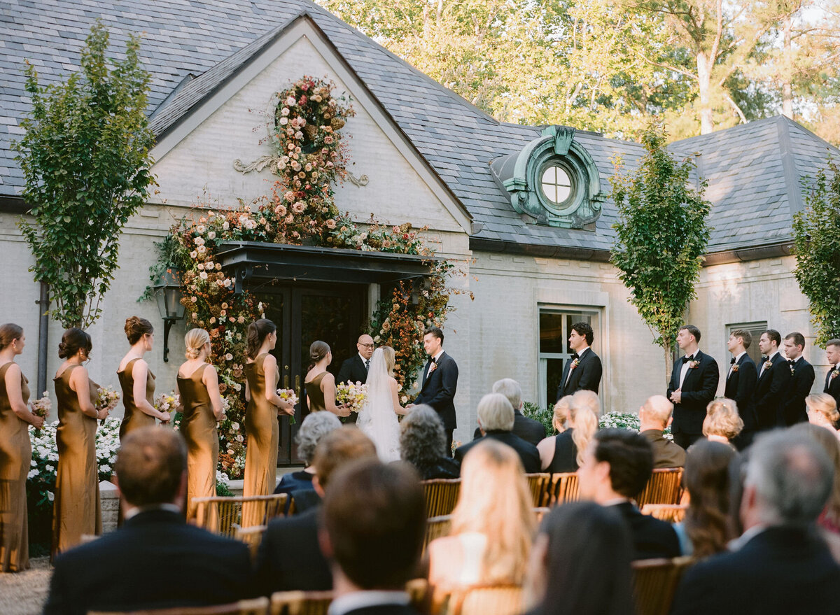 Organic growing floral installation for fall wedding ceremony backdrop. Private residence wedding build out for outdoor wedding ceremony and reception. Whimsical and organic floral design for autumnal wedding in colors of copper, yellow, blush, cream, and pops of orange. Clear tented wedding outside Nashville, TN. Design by Rosemary & Finch Floral Design in Nashville, TN.