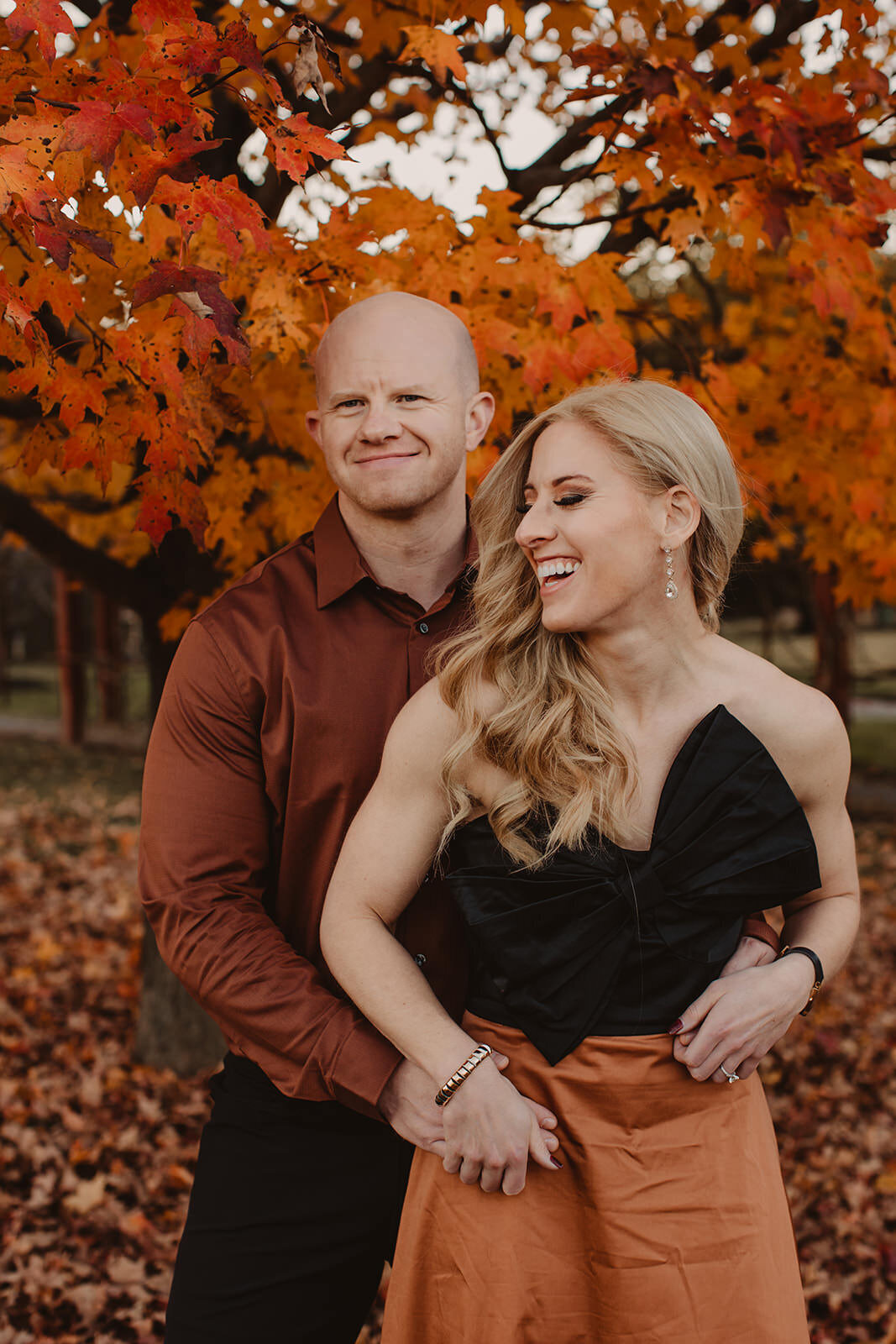 A person standing behind their partner with their arms around them as they smile