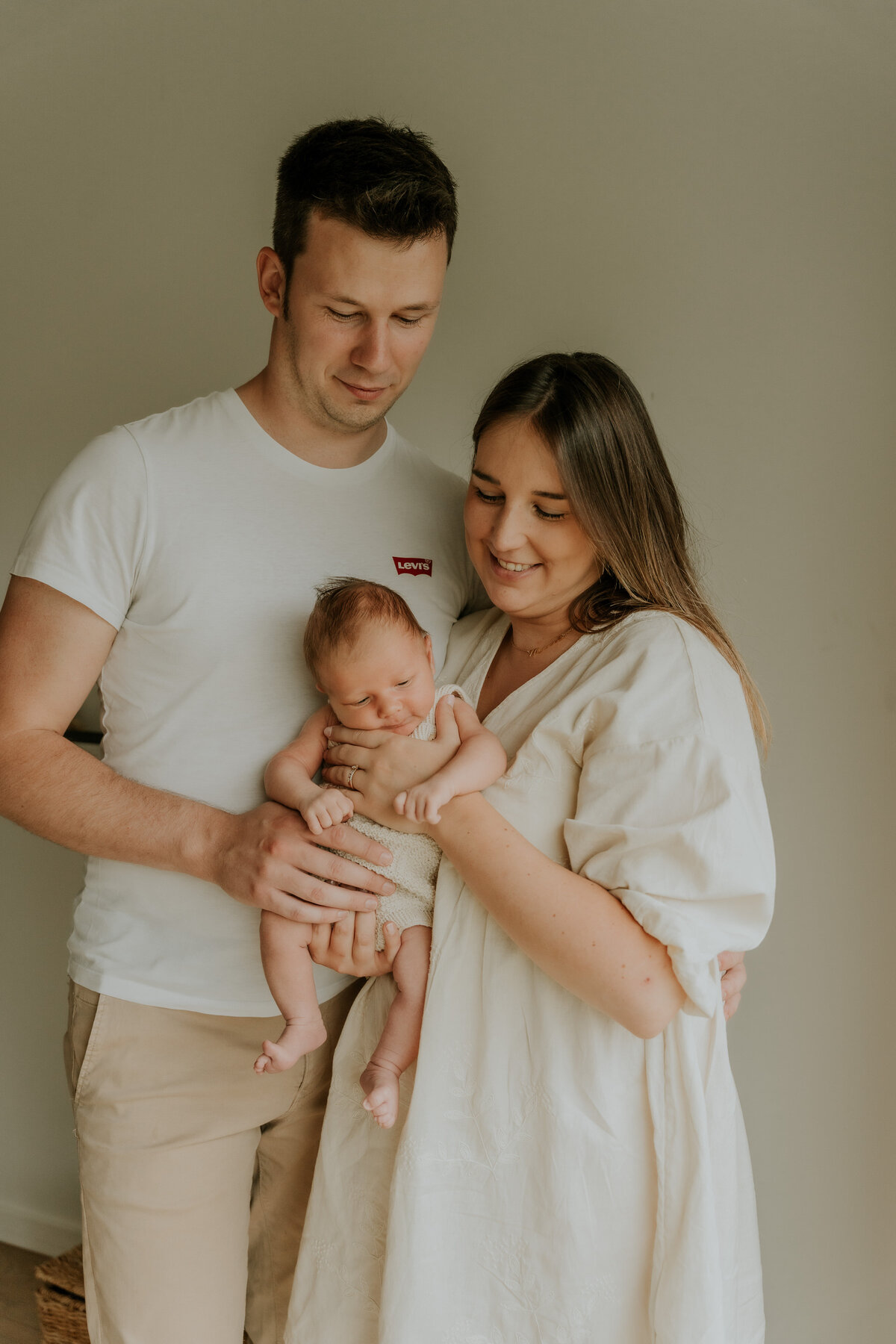 Newborn baby pose tussen de armen van de ouders.