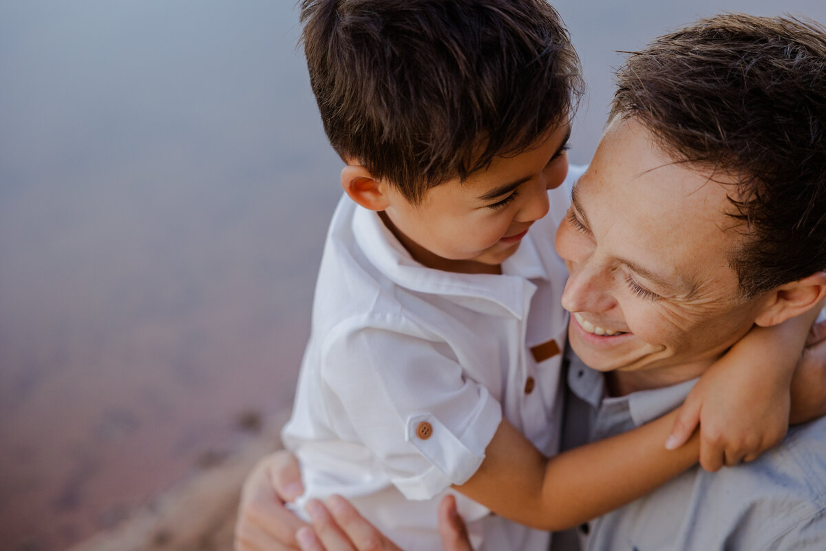 Dad laughing as his son wraps his arms around him, both smiling during their family photo session in Albury with Heartfully Captured Photography.