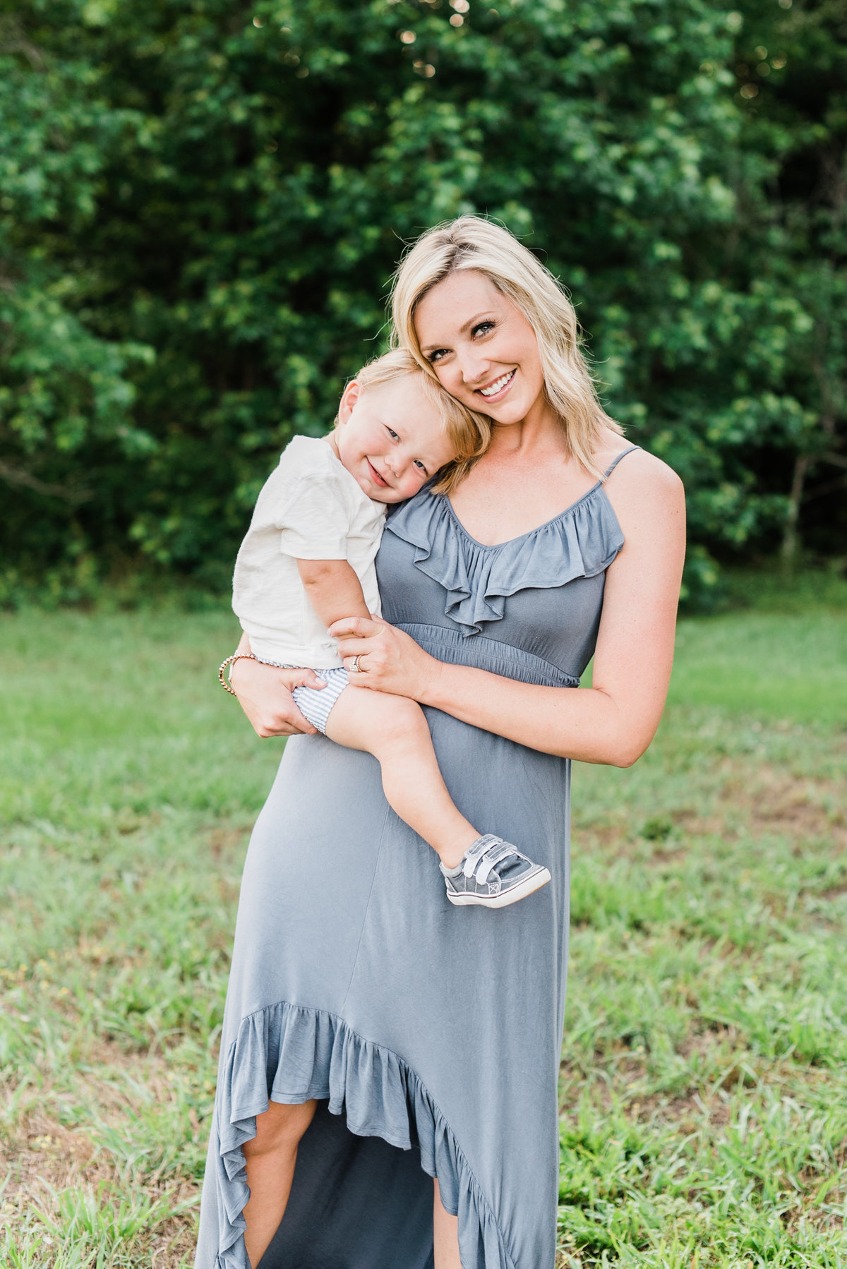 Mom holds her two year old son close while wearing a blue dress during a Raleigh family portrait session. Photographed by Raleigh NC family photographer A.J. Dunlap Photography.