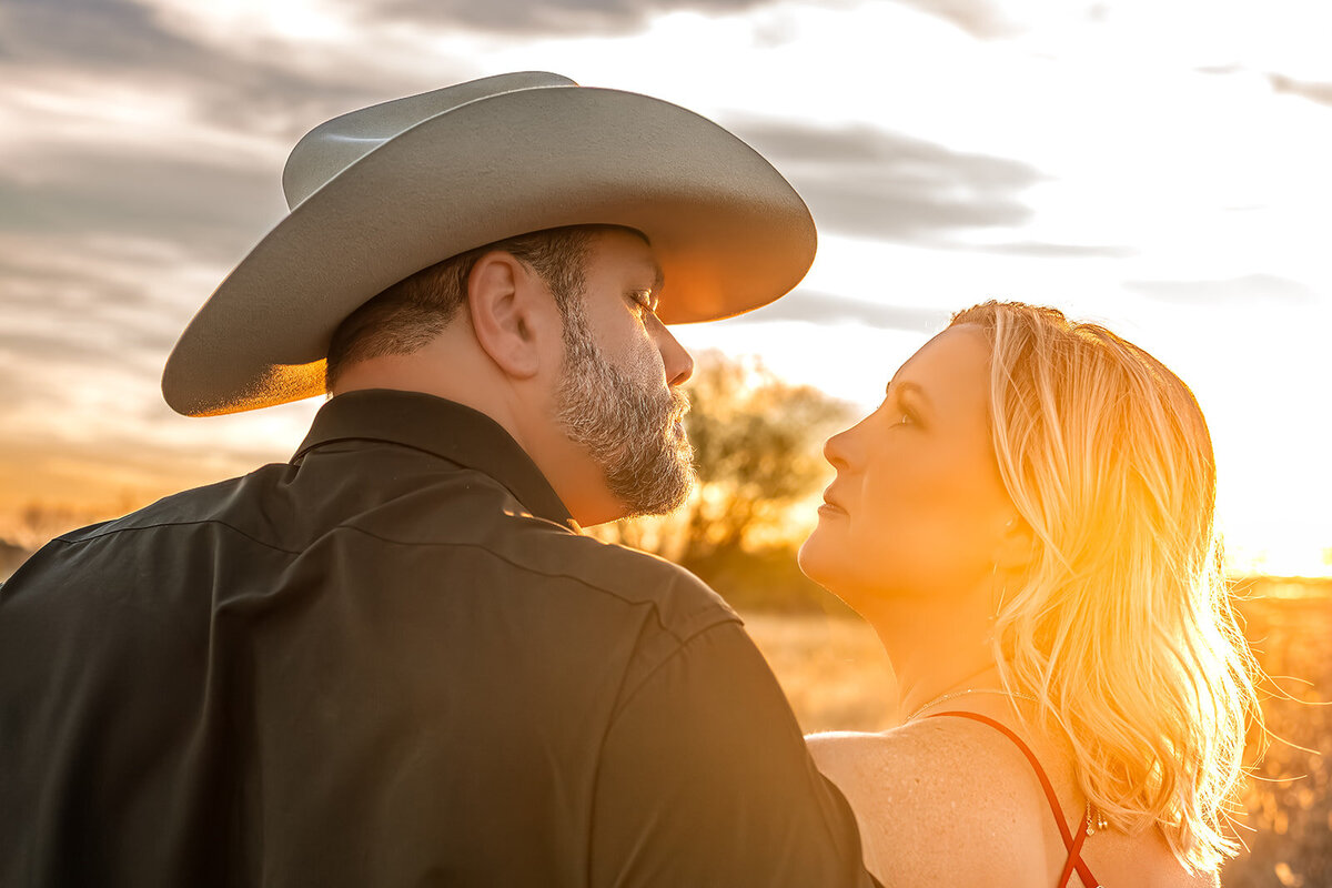 Close-up of engaged couple looking at each other with sunset glow between their faces during engagement session in New Braunfels, Texas.