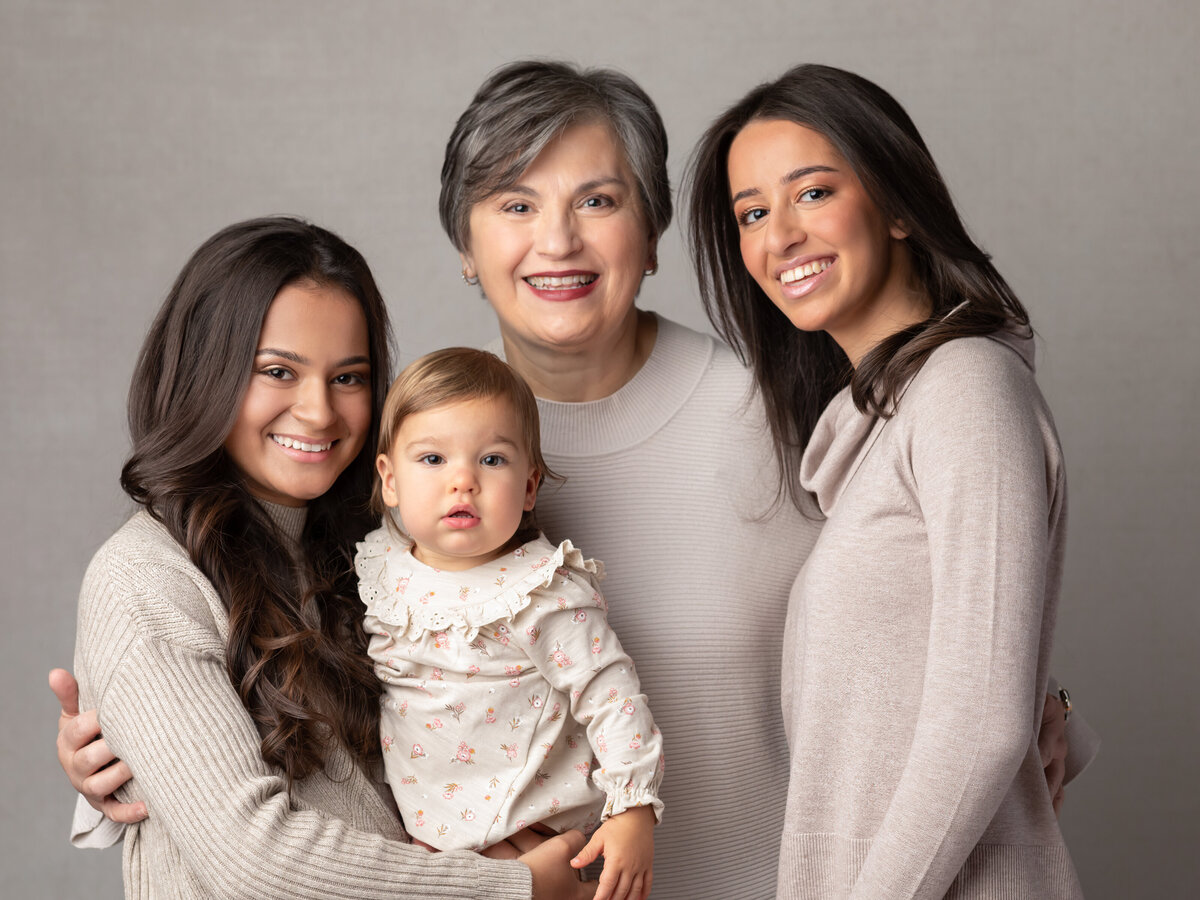 grandma and three granddaughters posing for studio portraits