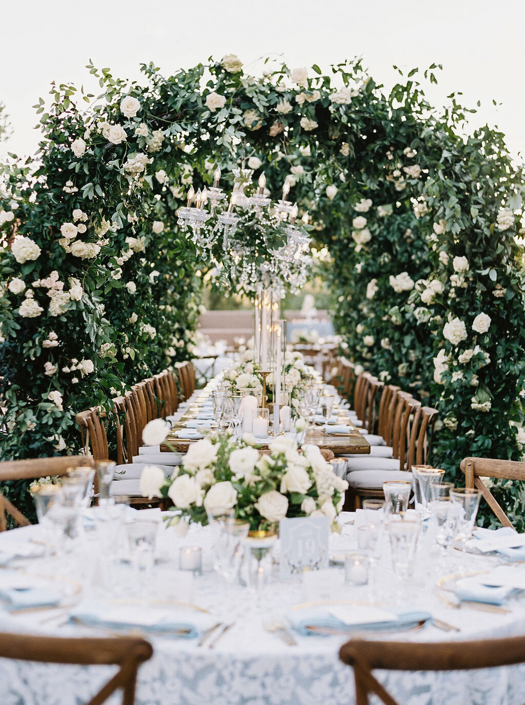 A breathtaking wedding reception setup with a floral archway, crystal chandeliers, and elegant tablescape. Perfect for couples seeking luxury wedding inspiration.