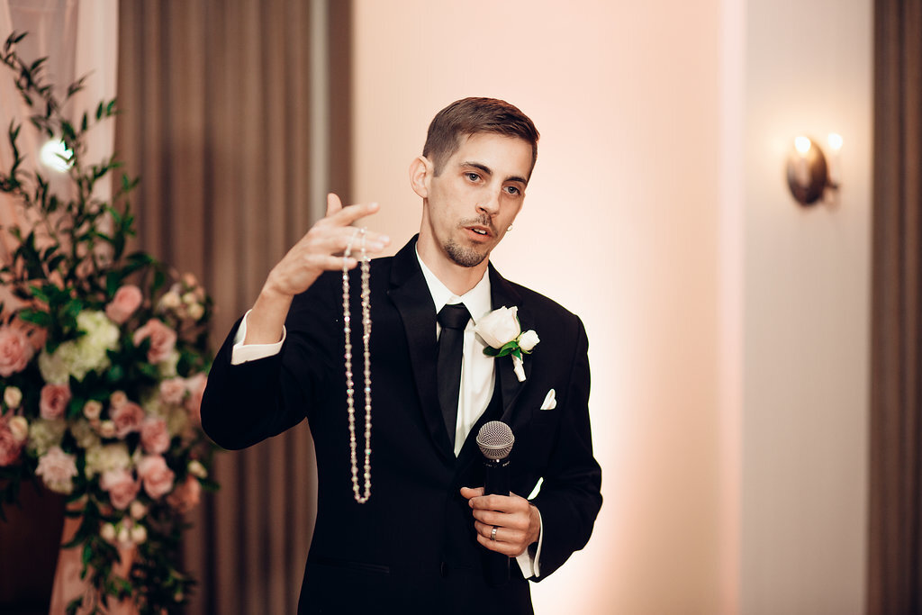 Wedding Photograph Of Groom In Black Suit Holding a Necklace Los Angeles