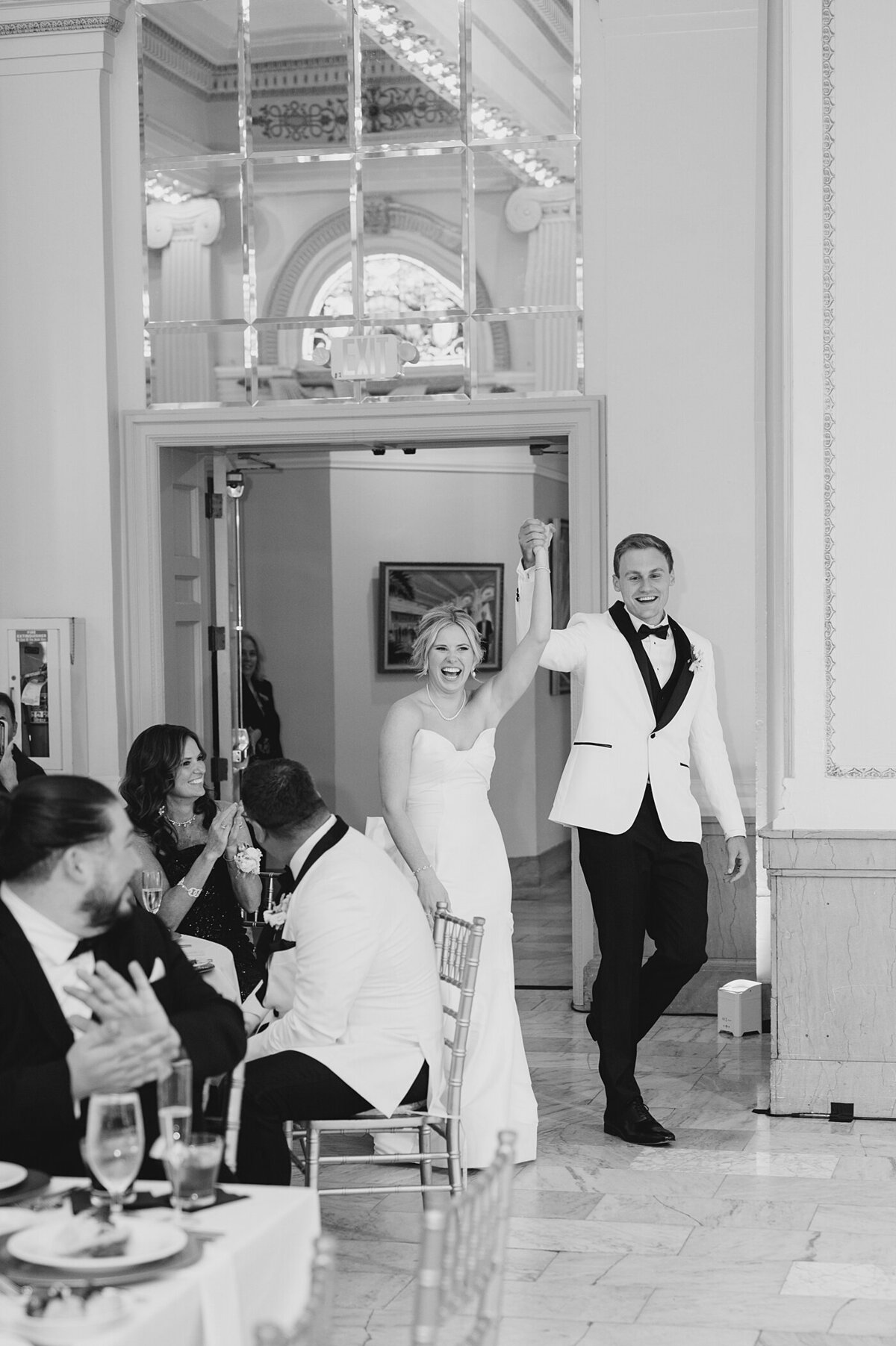 bride and groom entering the Westin wedding reception with their hands held together in the air in celebration as they enter their reception