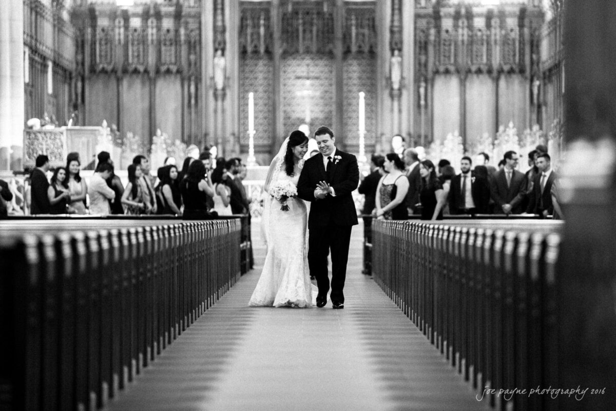 A bride and groom walking back up the aisle after their wedding.