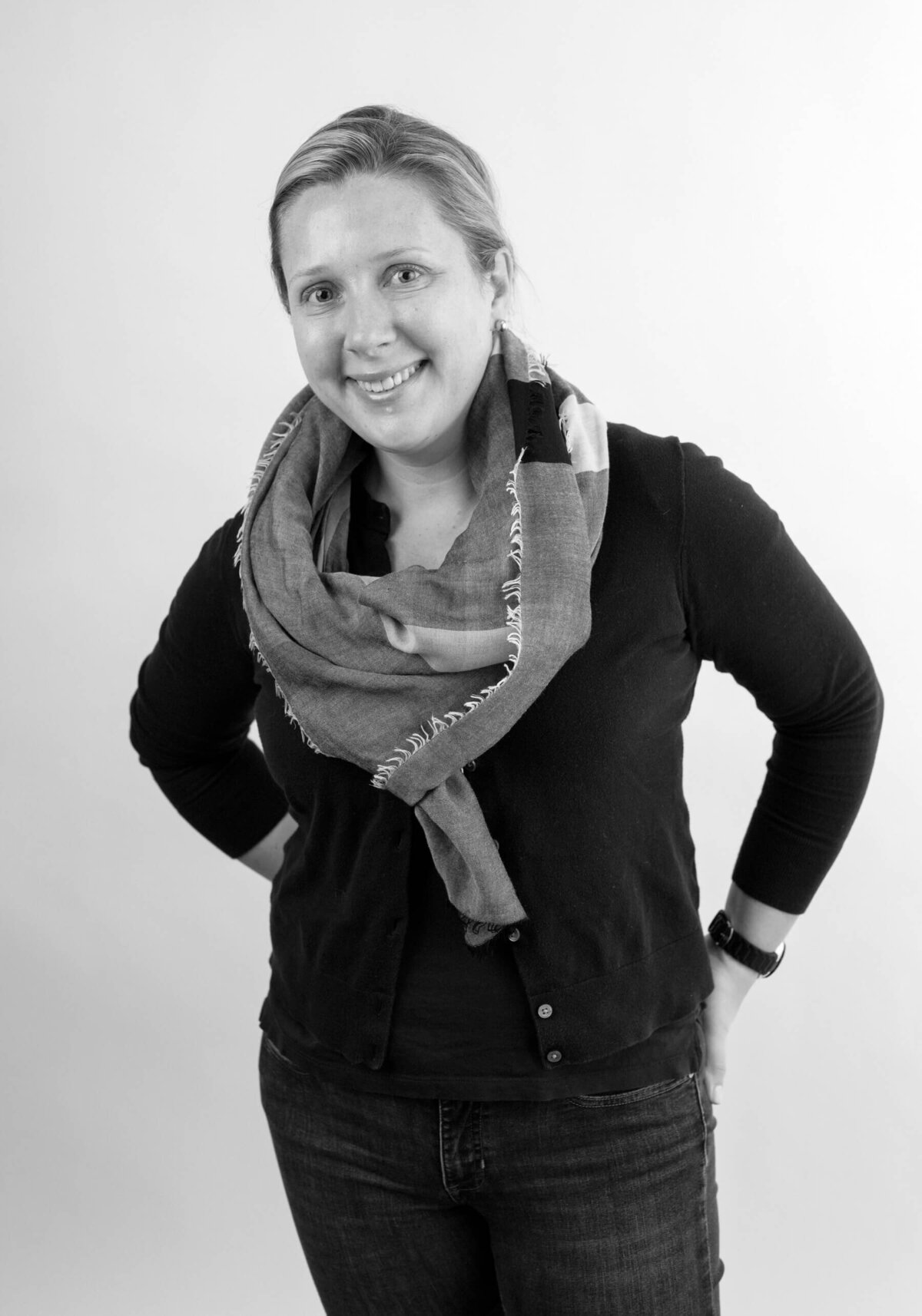 Before shot of a woman in a black sweater and scarf, smiling warmly at the camera.