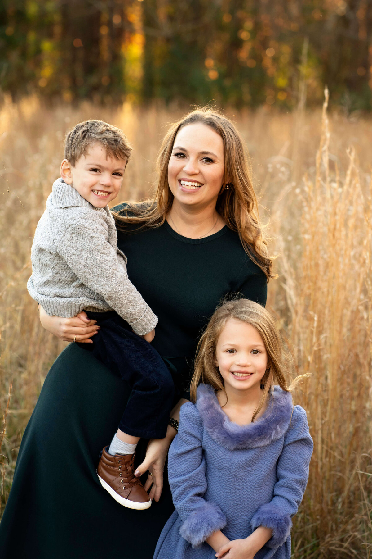 Mother standing in field of tall grass with son and daughter