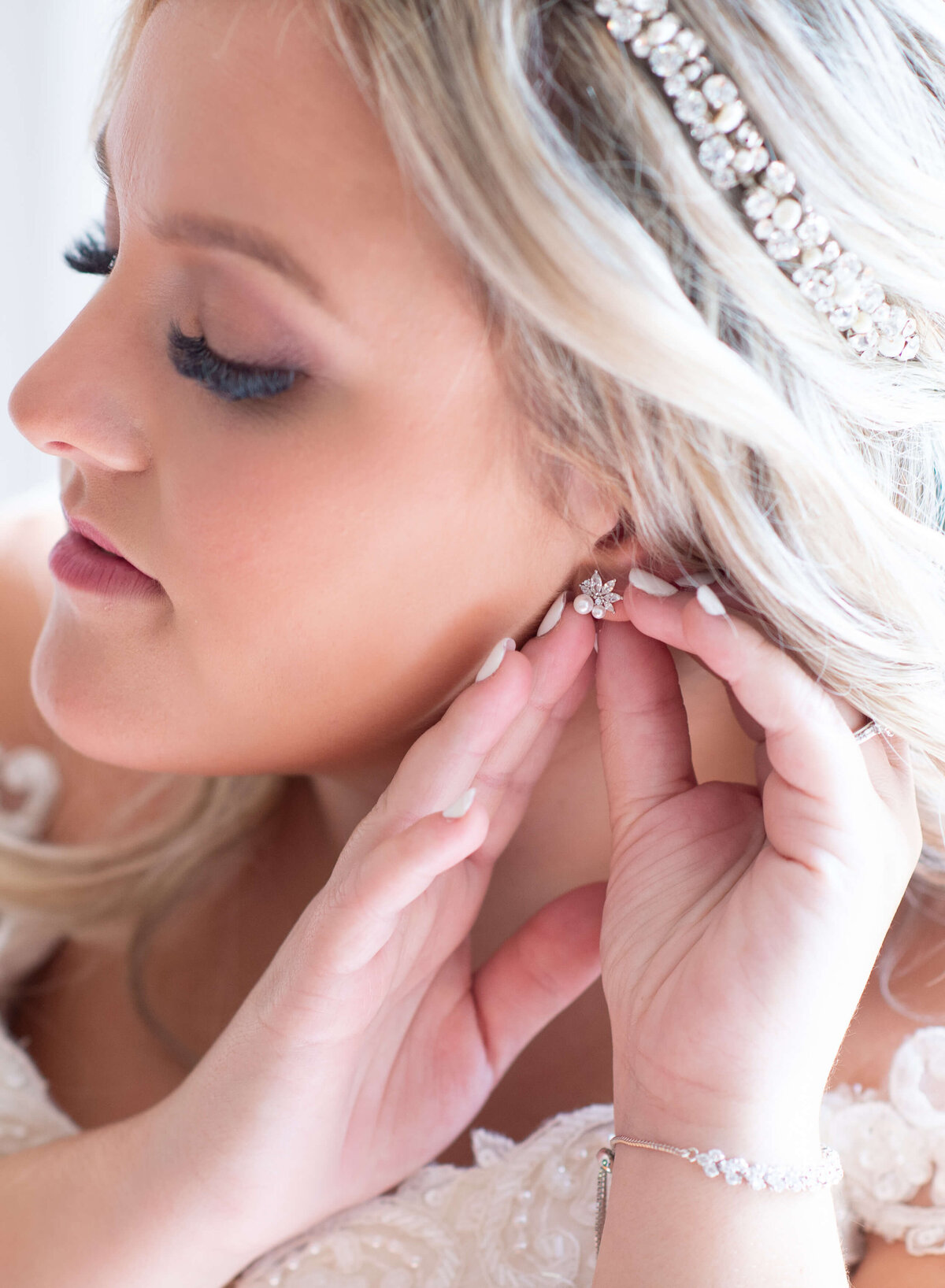 a photo of a bride putting on her earrings  and bridal accessories as she gets ready for her Ottawa wedding.