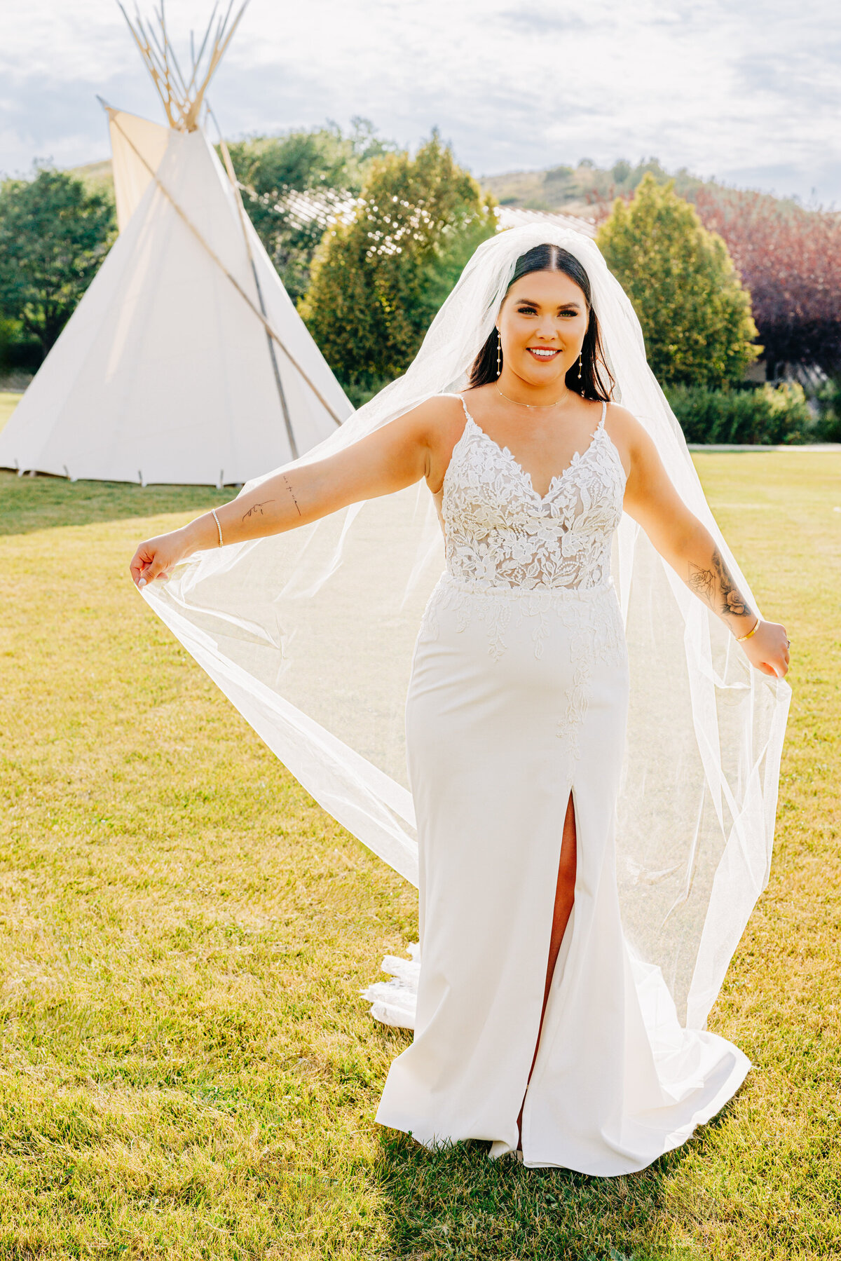 Portrait of Montana bride wearing long veil standing in front of tipi