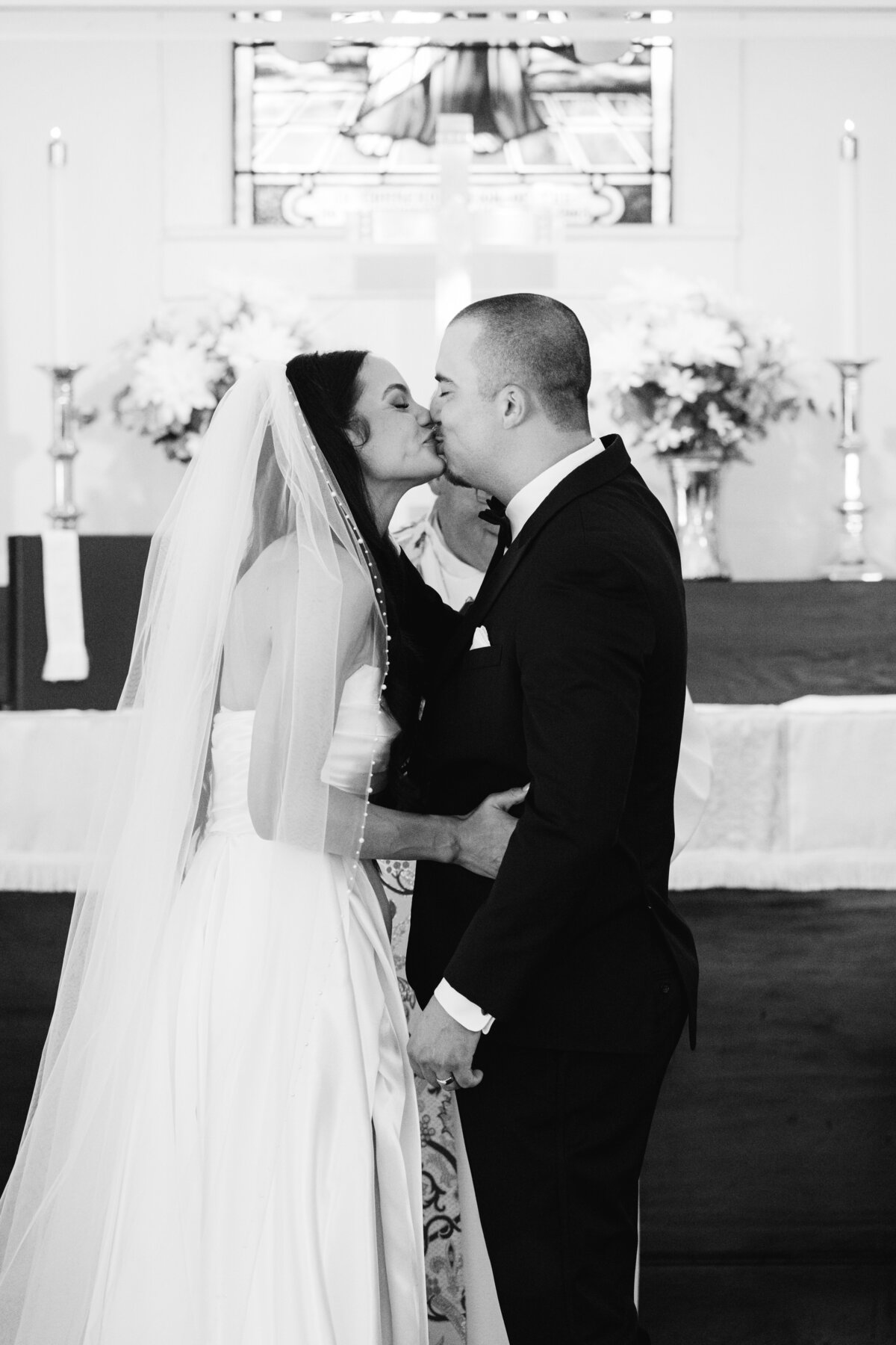 bride and groom kiss at church alter