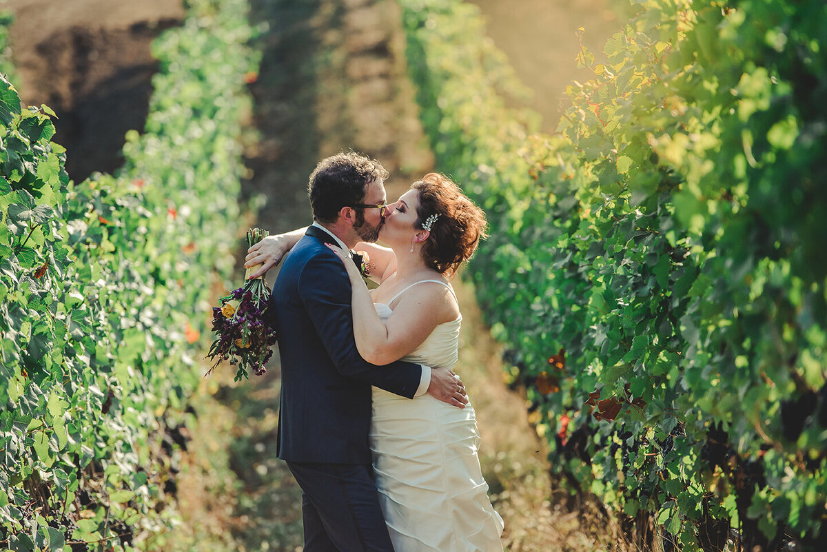 bride and groom kissing in vineyard
