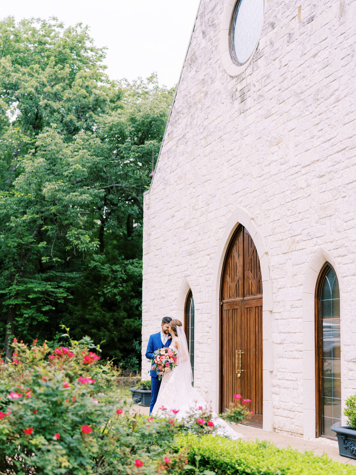 Bride and groom standing outside Ashton Gardens wedding chapel in garden