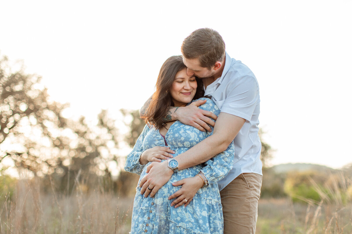 Maternity portrait of a pregnant woman with her family in a field, photographed by San Antonio family photographer Sara James.