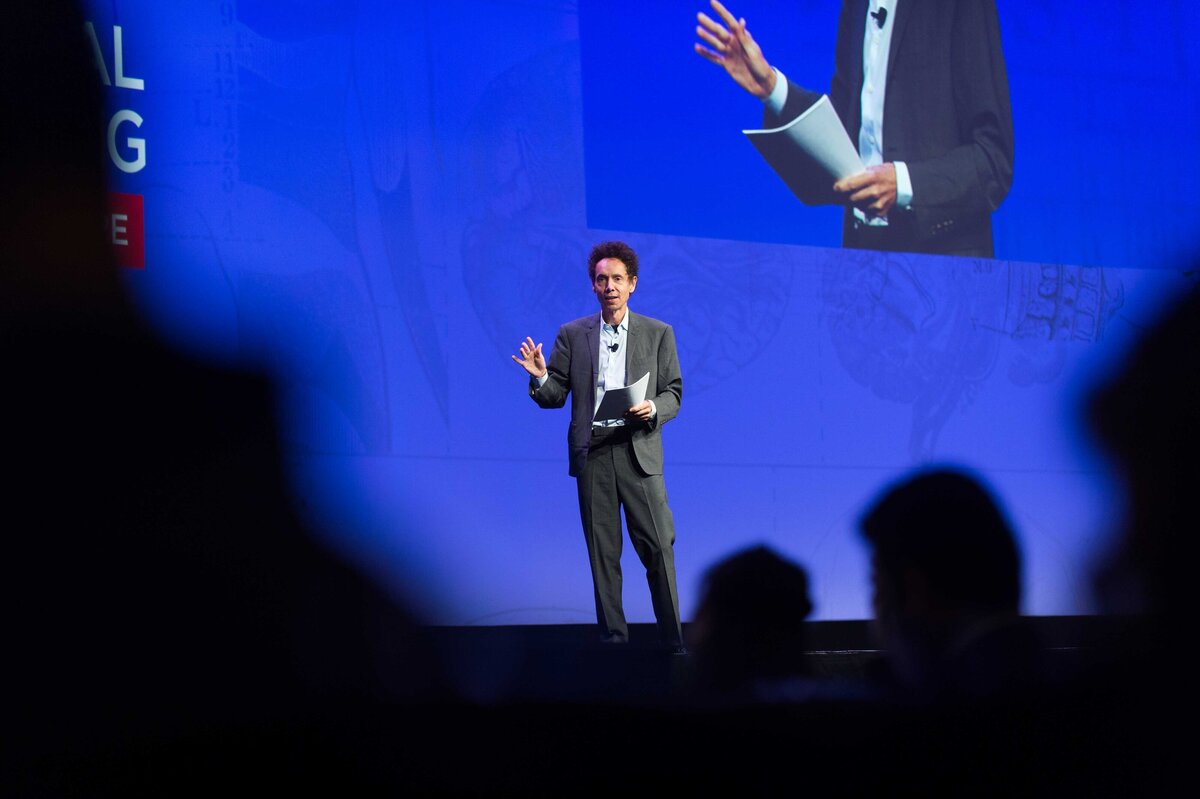 Malcolm Gladwell speaks from stage at General session