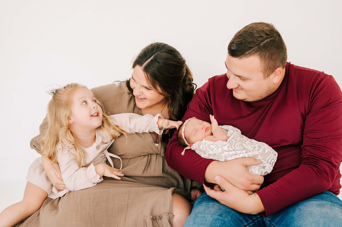Springfield newborn photographer Jessica Kennedy of The XO Photography captures toddler girl laughing with parents holding newborn