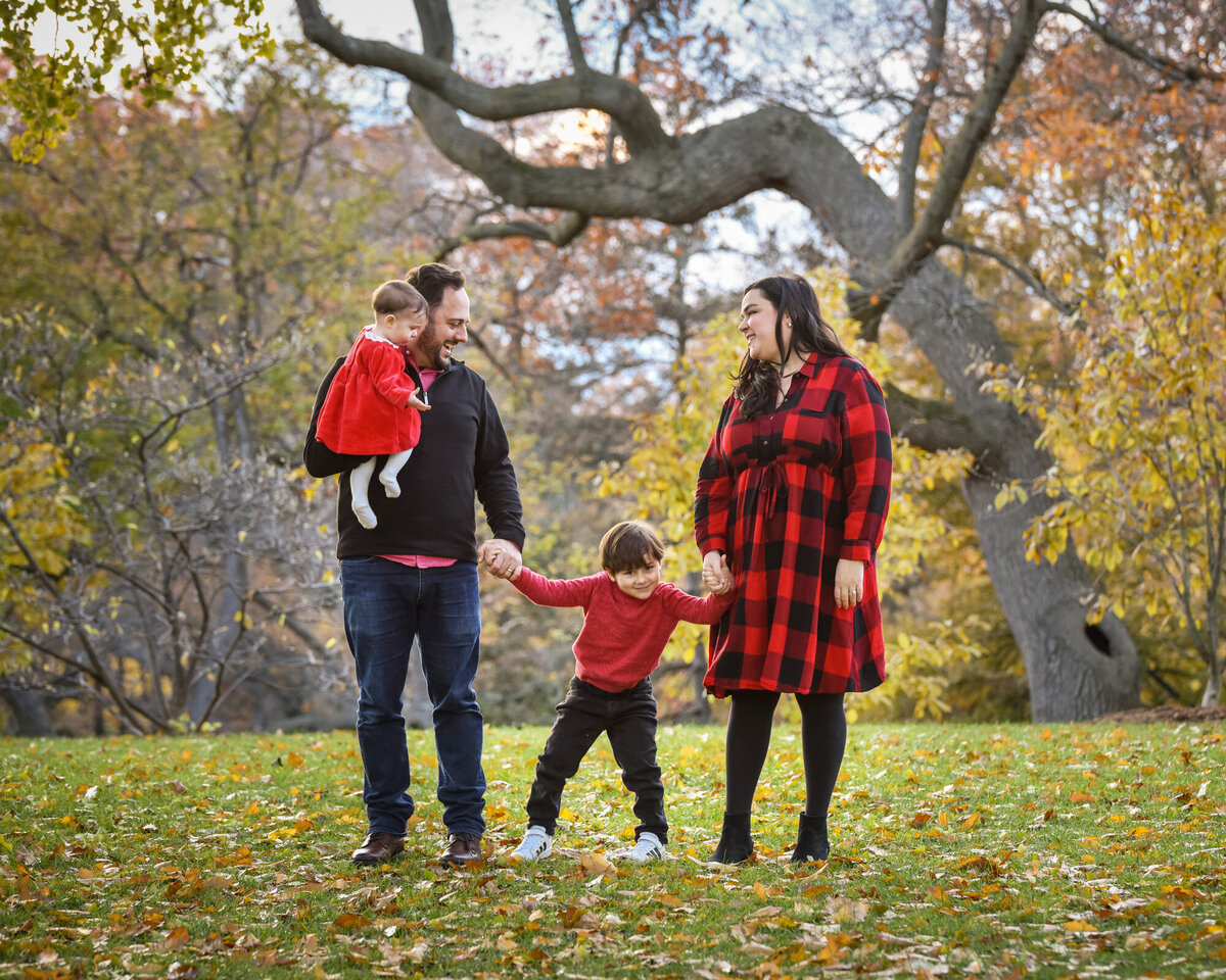 Family portrait in the fall outdoor kicking leaves in park