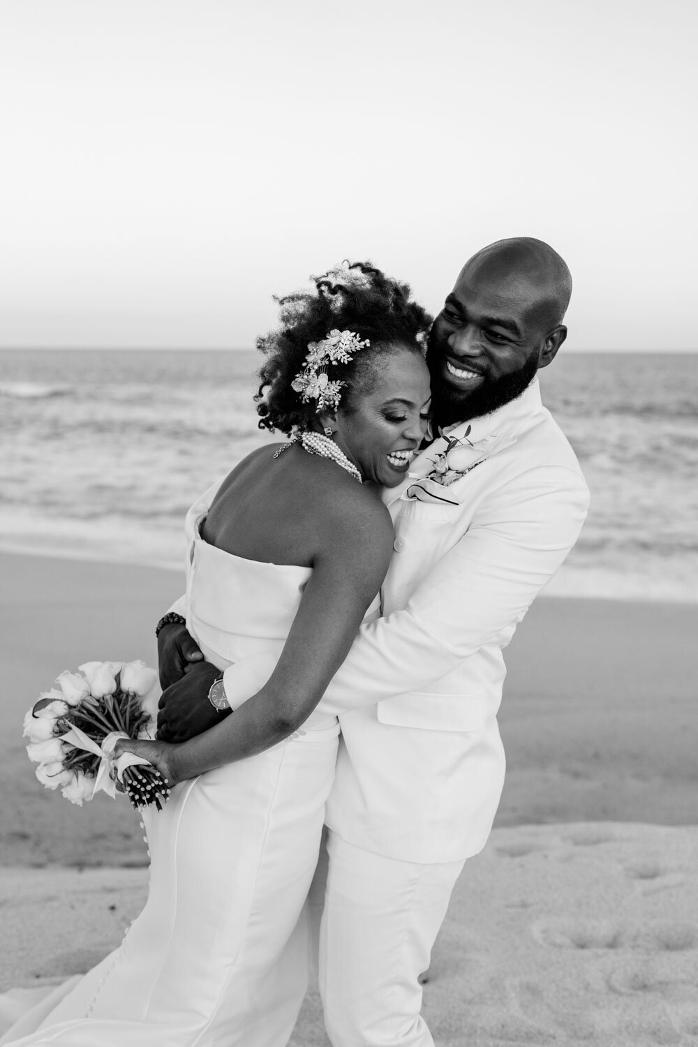 Black and white photo of of bride and groom embracing, both smiling softly