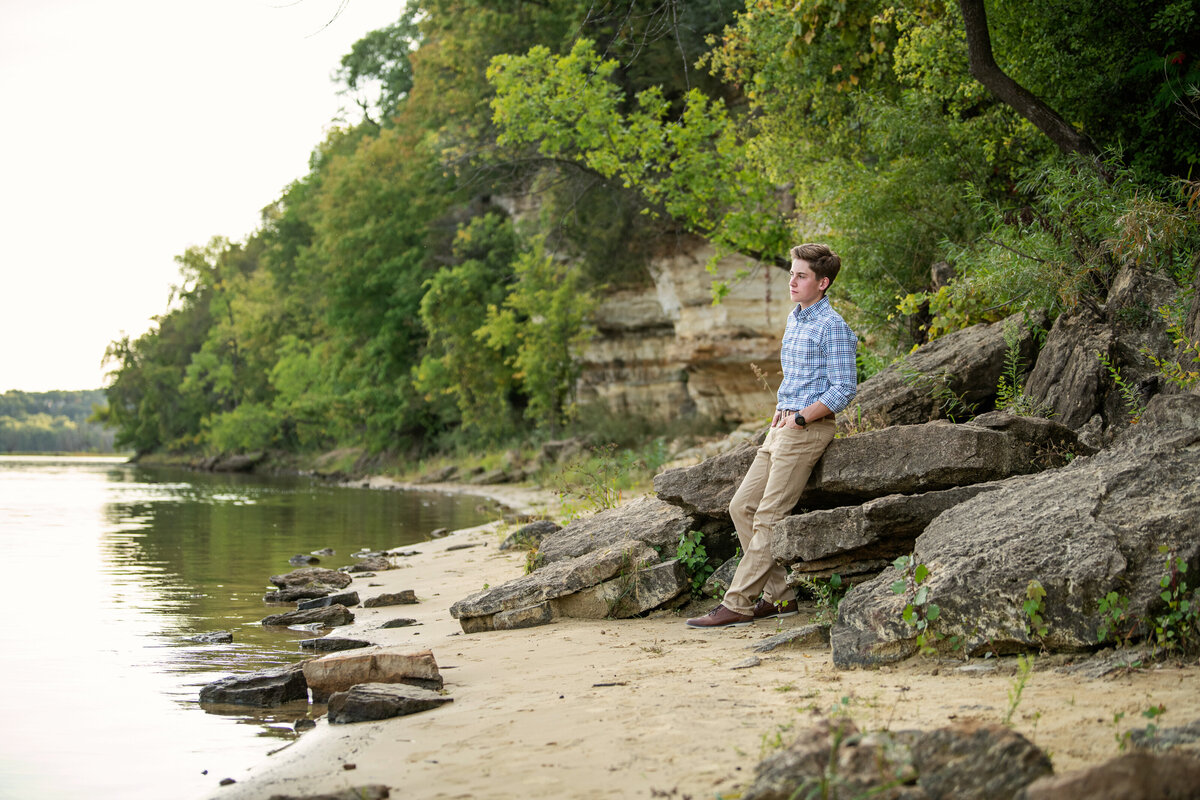 senior picture of guy leaning against rock by St. Croix River