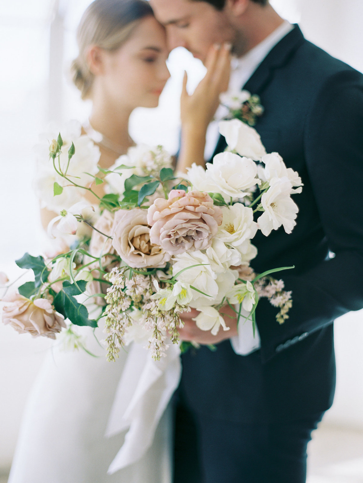couple holding garden rose boquet in neutral tones