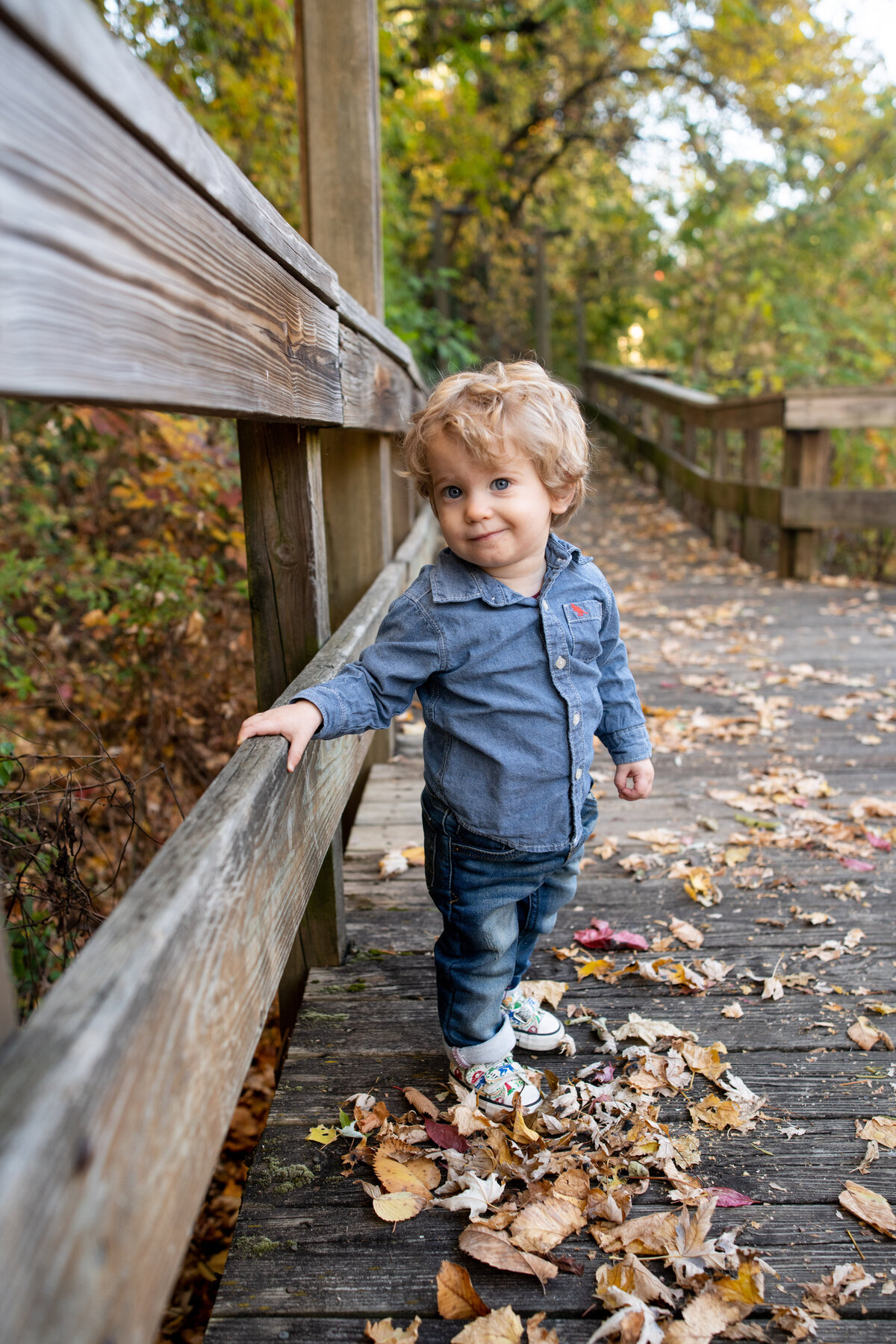 toddler walks along  leaf covered boardwalk in cuyahoga falls