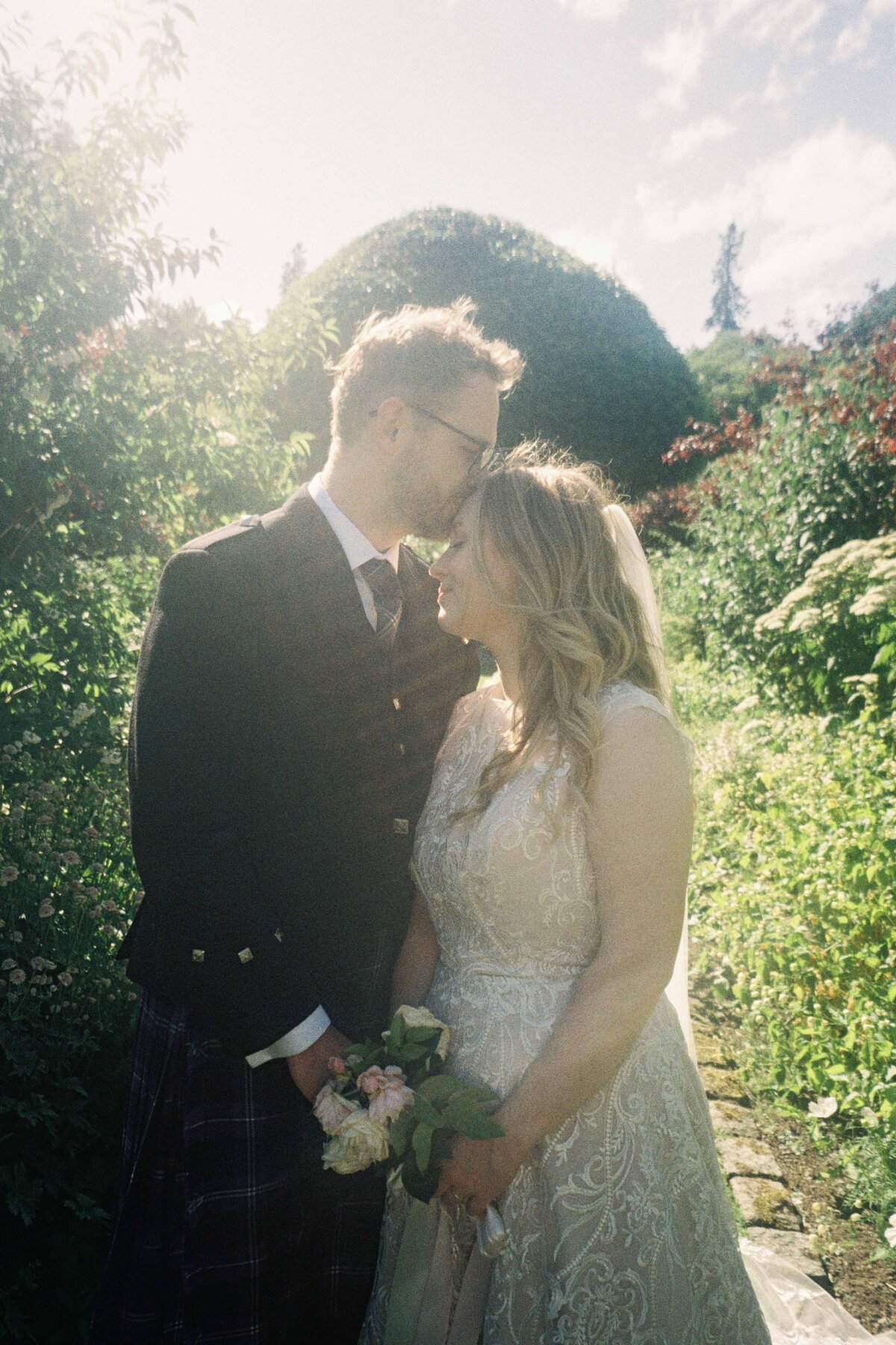 A bride hold a grooms hand and they are photographed on 35mm film after their wedding.