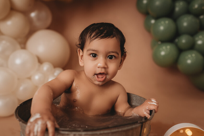 Cake smash milestone session with Atlanta, Georgia cake smash photographer. Milestone photography session with earthy tones, balloon garland and sweet baby boy eating cake for his first birthday.