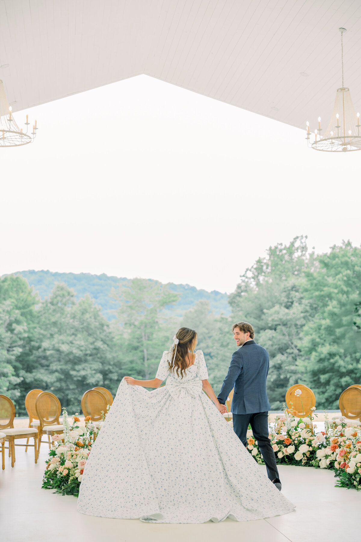 Bride and Groom walking out of the ceremony site overlooking gorgeous hills at the ivy rose barn