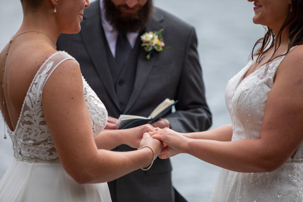 Two brides stand holding hands during their elopement ceremony.