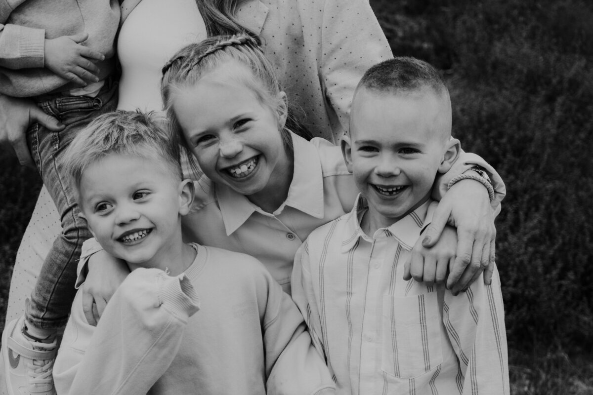 Zwart-witfoto van een gezin met twee jongens en een meisje, die samen poseren in een warme, liefdevolle omgeving.