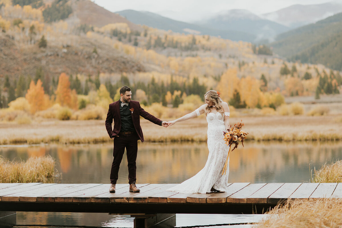 Bride and groom standing on a dock holding hands