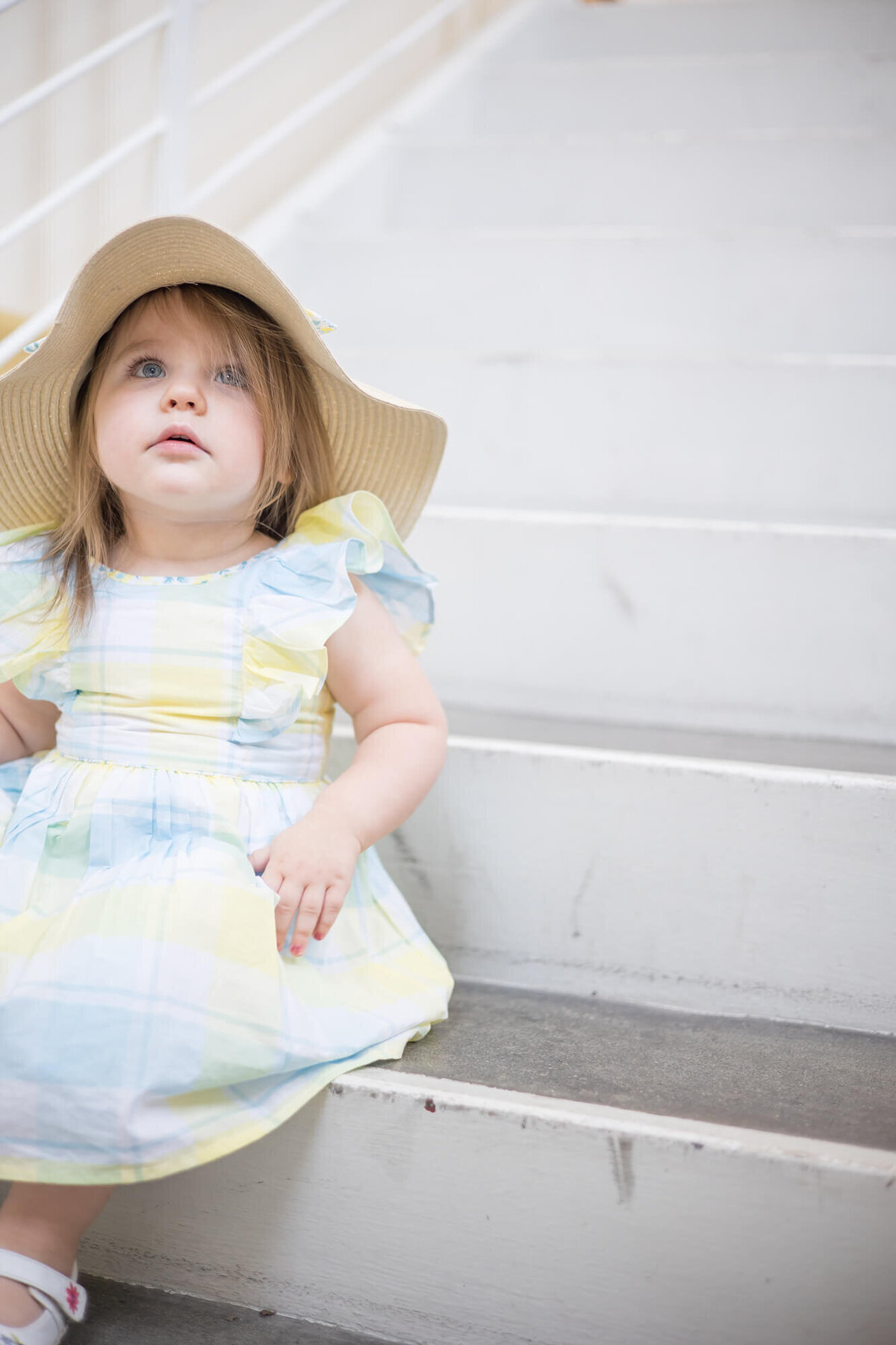 2 year old girl sitting on the stairs looking up