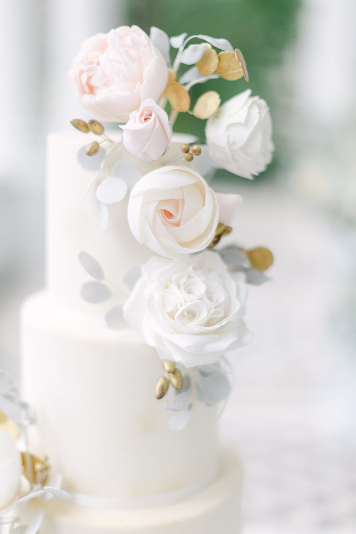 Detail of a bespoke white wedding cake with hand made sugar roses designed by ECLAT Destination Weddings Vienna