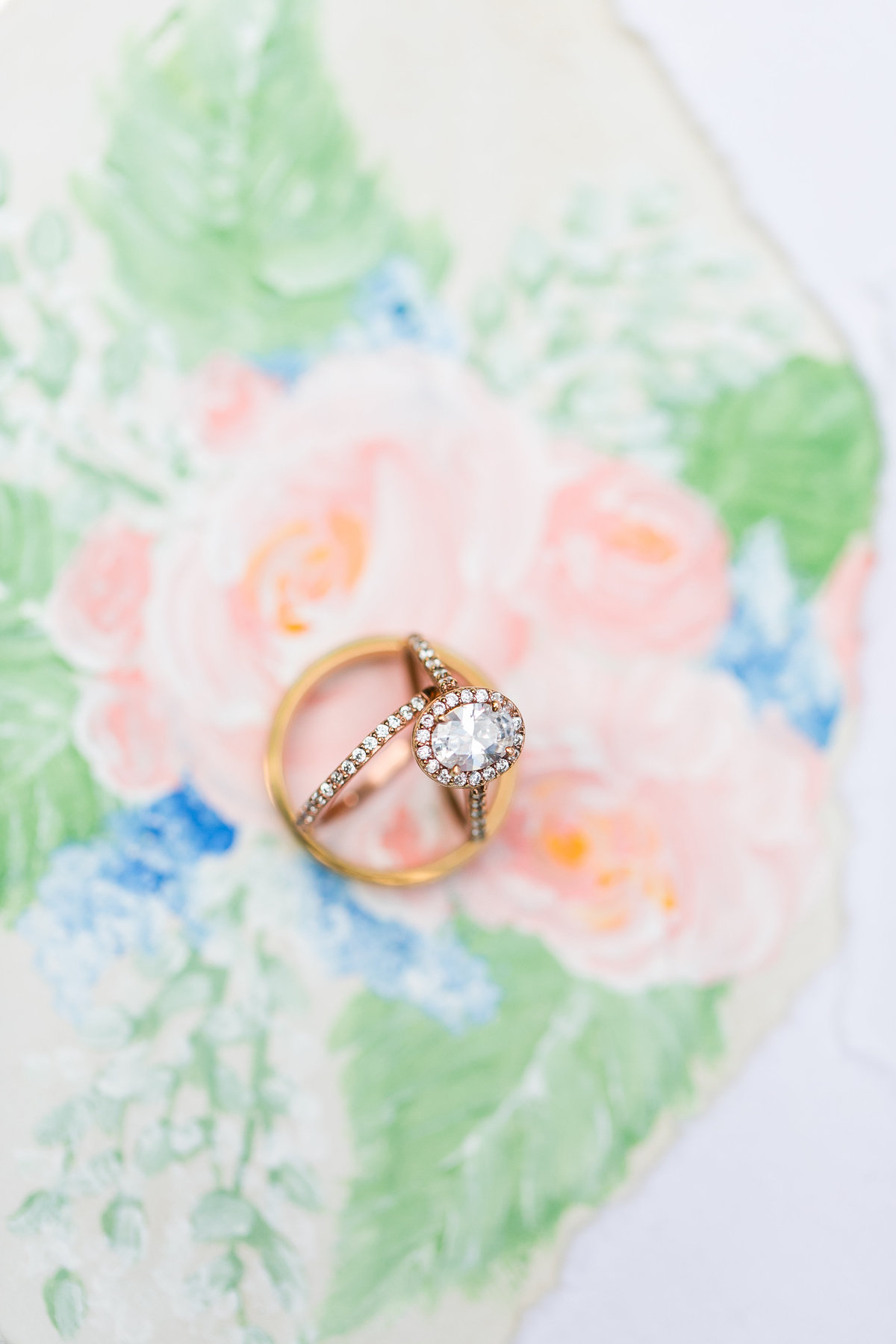 Ring shot on top of custom painted floral elements of invitation suite