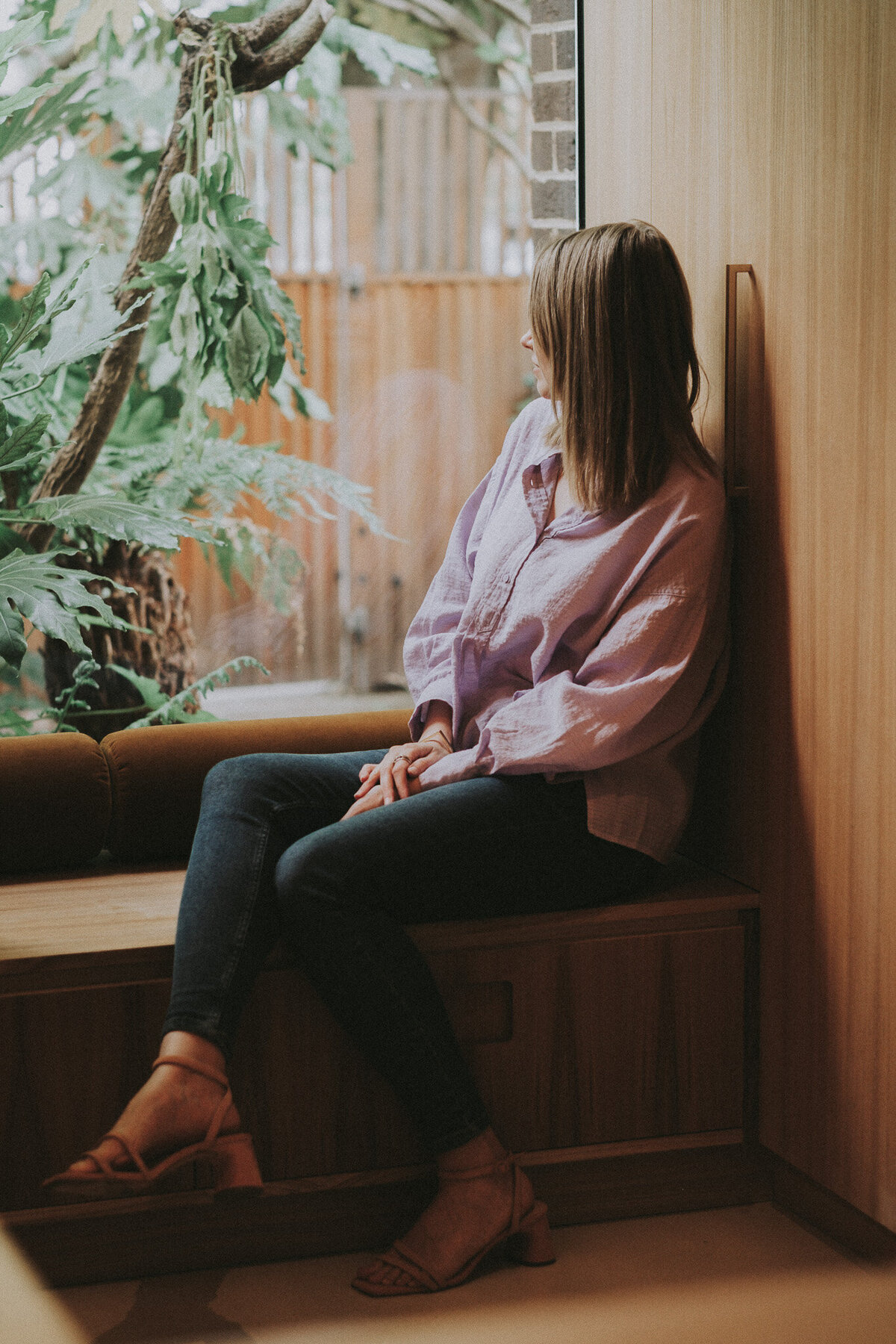 Young Business Woman Sitting In Window Looking At Tree