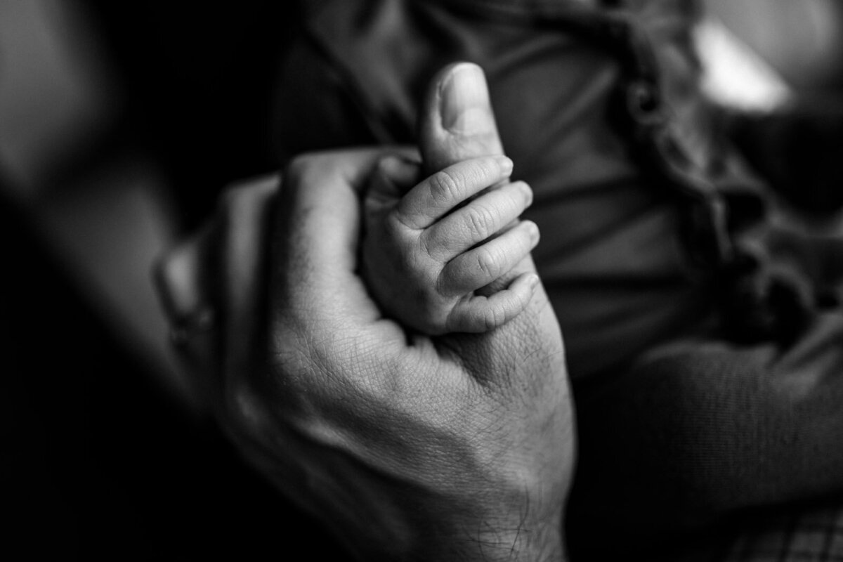 newborn fingers wrapped around dad's thumb
